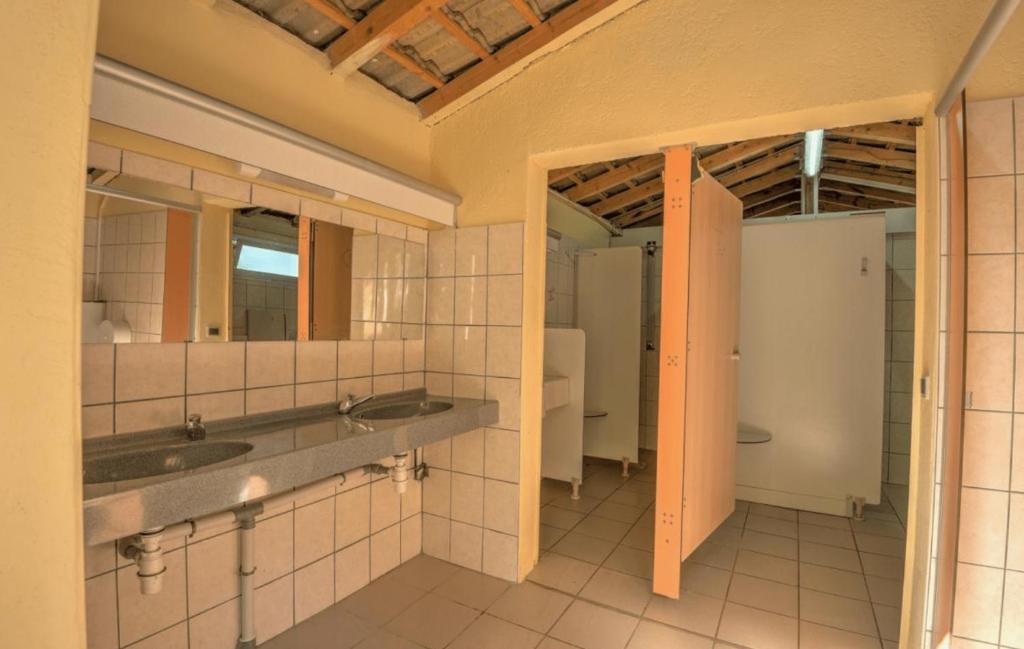 une salle de bain avec deux lavabos et un miroir dans l'établissement Camping du Vignal, à Lablachère