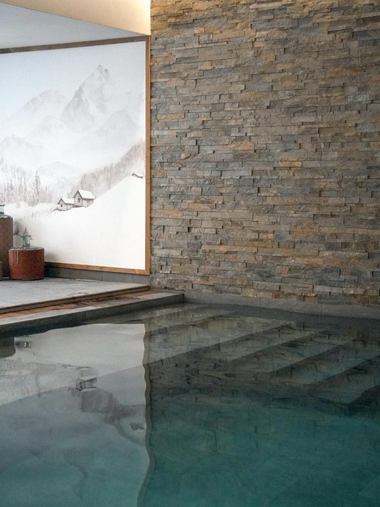 Cette chambre dispose d'une piscine et d'une peinture sur un mur en briques. dans l'établissement Résidence l'Ecrin d'Argent by My Mountain Resort, à Valmorel