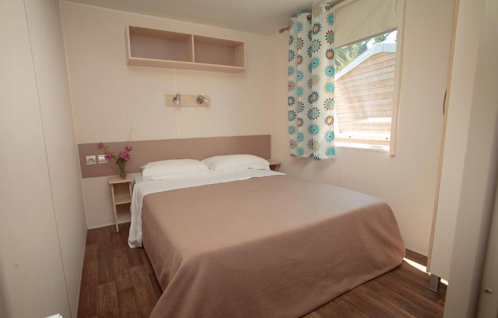une petite chambre avec un lit et une fenêtre dans l'établissement Domaine Résidentiel de Plein Air Les Demoiselles, à Saint-Hilaire-de-Riez
