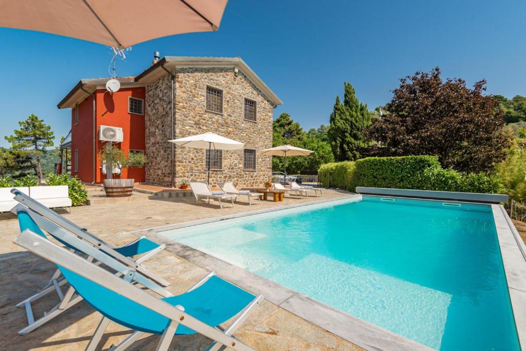 une piscine avec des chaises et une maison dans l'établissement Villa Emozione, à Sarzana