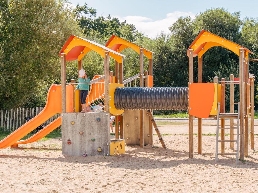 - une aire de jeux avec des équipements orange et orange dans le sable dans l'établissement Domaine Résidentiel de Plein Air Le Vorlen, à Fouesnant