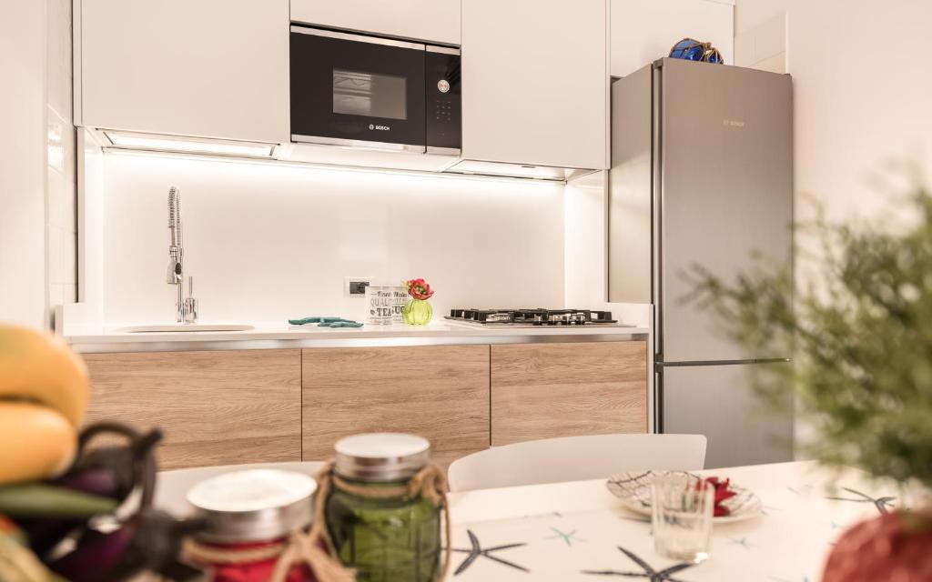 La cuisine est équipée d'une table, d'un four micro-ondes et d'un réfrigérateur. dans l'établissement Costa Rica Bibione Eco Resort, à Bibione