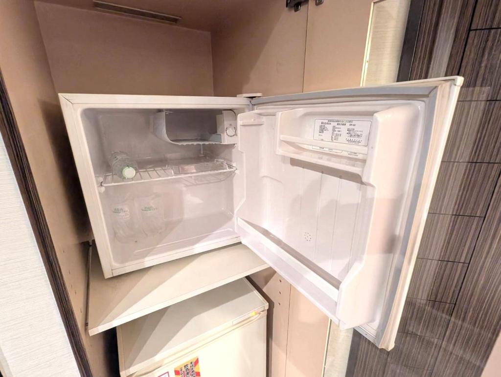 un réfrigérateur vide avec sa porte ouverte dans une cuisine dans l'établissement HOTEL Pierrot 泉大津, à Izumiotsu