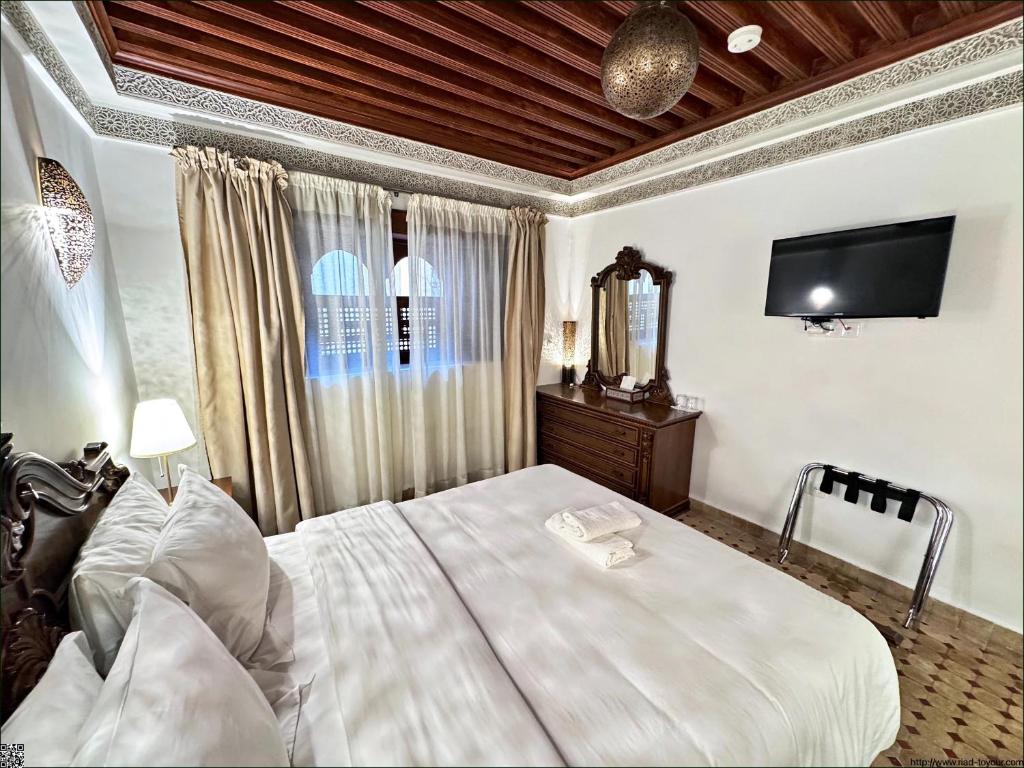 une chambre avec un lit et une télévision au mur dans l'établissement Riad Toyour- Riad of birds, à Fès