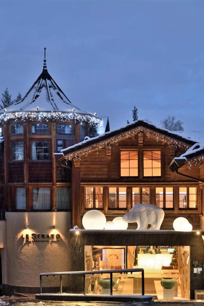 une grande maison en bois avec des lumières sur la façade dans l'établissement Le Strato, à Courchevel