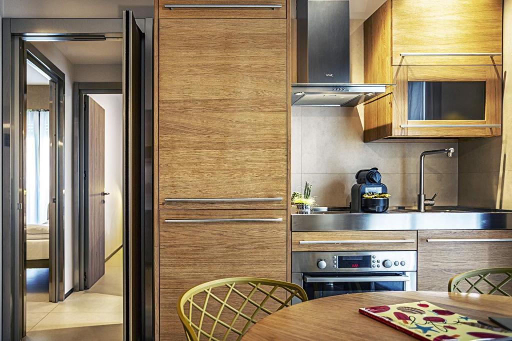 une cuisine avec des armoires en bois et une table avec des chaises dans l'établissement Costa Rica Bibione Aparthotel, à Bibione 70 autres photos