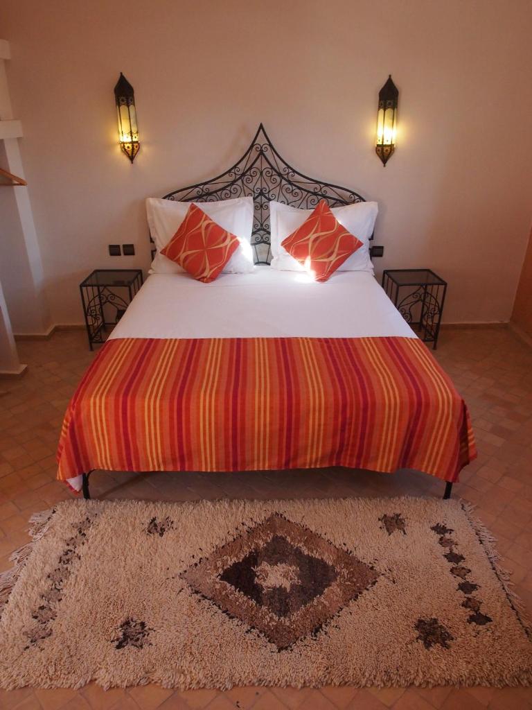 - une chambre dotée d'un grand lit avec des oreillers rouges et oranges dans l'établissement Riad Bouchedor, à Ouarzazate
