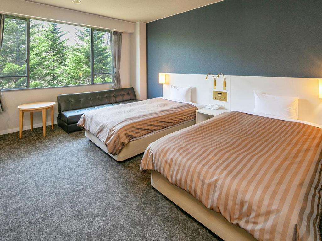 une chambre d'hôtel avec deux lits et une fenêtre dans l'établissement Itoen Hotel Kusatsu, à Kusatsu
