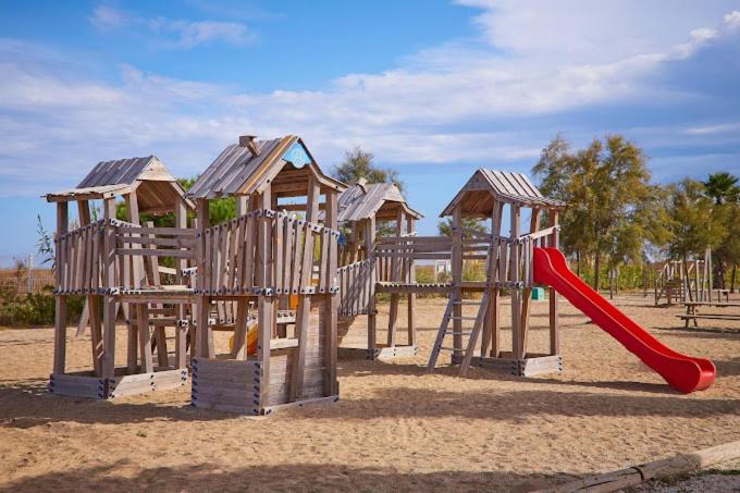 une aire de jeux en bois avec toboggan rouge et toboggan rouge dans l'établissement Camping les dunes 5 étoiles - Mobil Home 6 personnes, à Torreilles