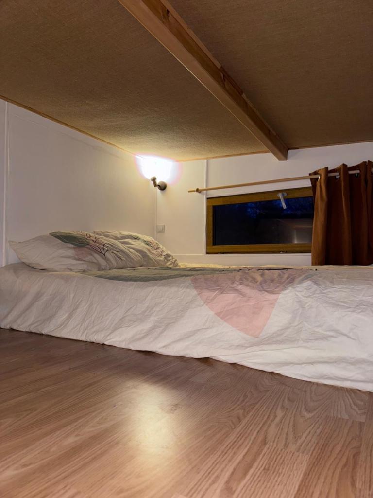 un lit dans une petite pièce avec une fenêtre dans l'établissement Tiny house au coeur de la foret, à Les Martys