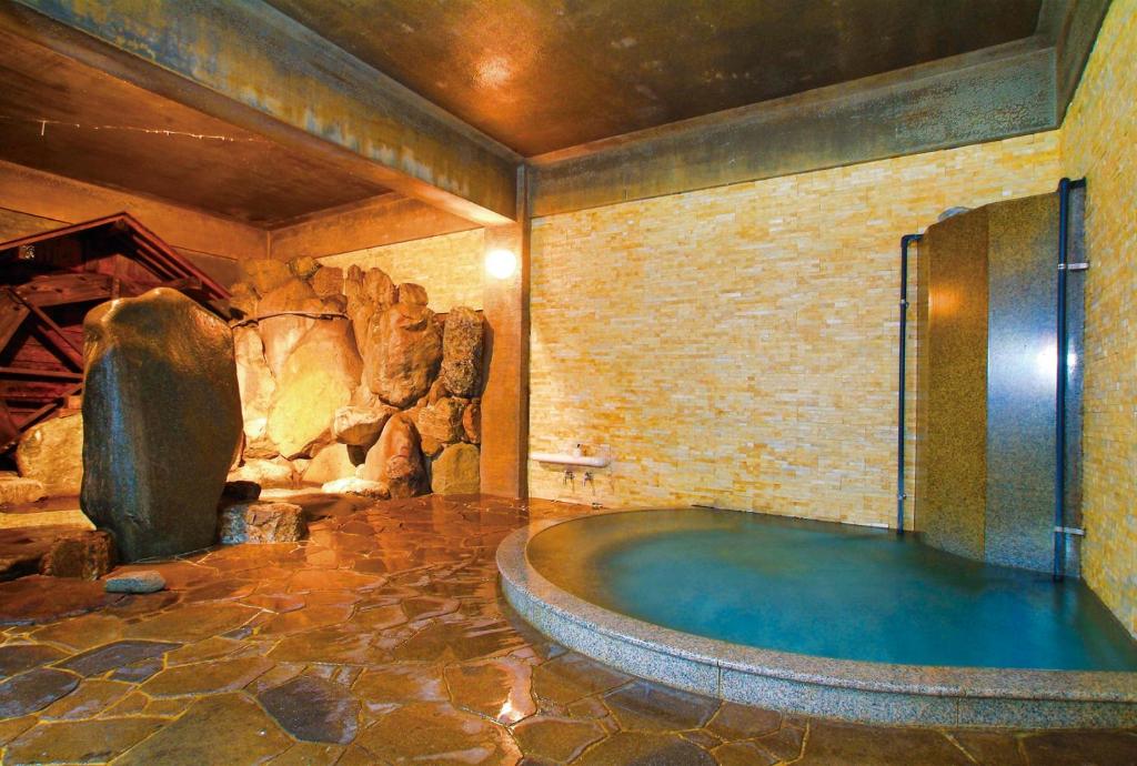 - une grande salle de bains avec baignoire dans une chambre ornée de rochers dans l'établissement Irori Houraku, à Kamikawa