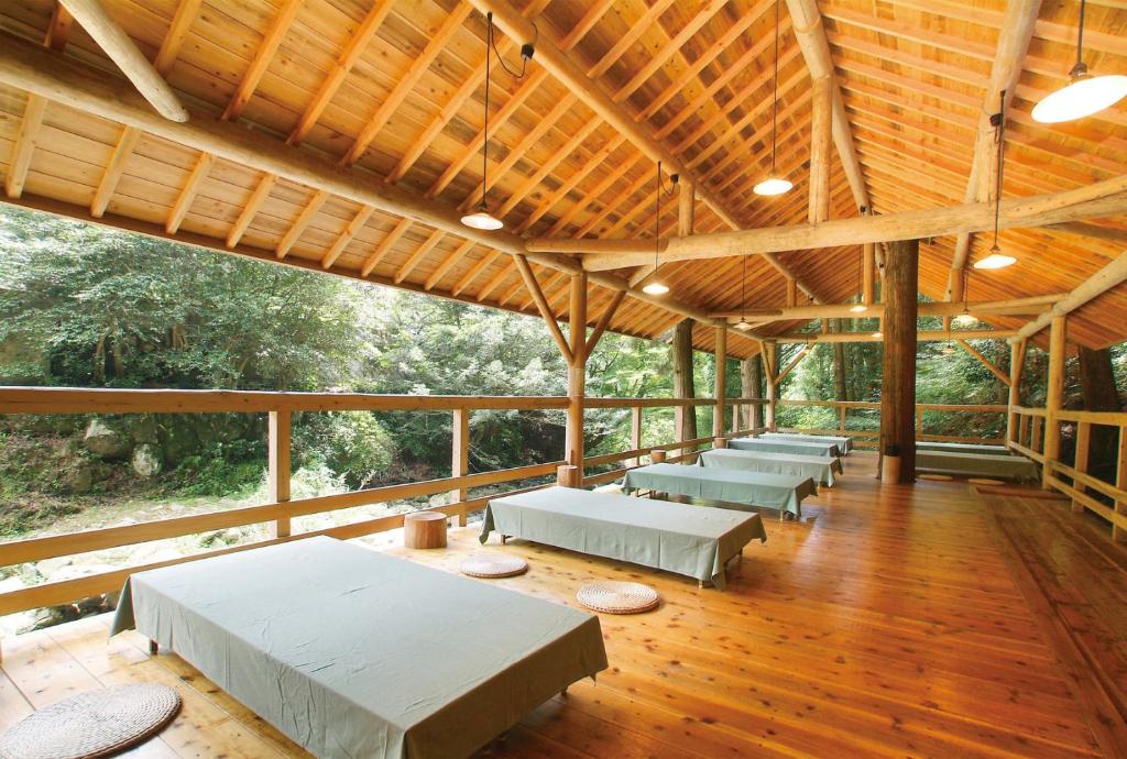 - un grand pavillon avec des tables et des bancs sur du parquet dans l'établissement Irori Houraku, à Kamikawa