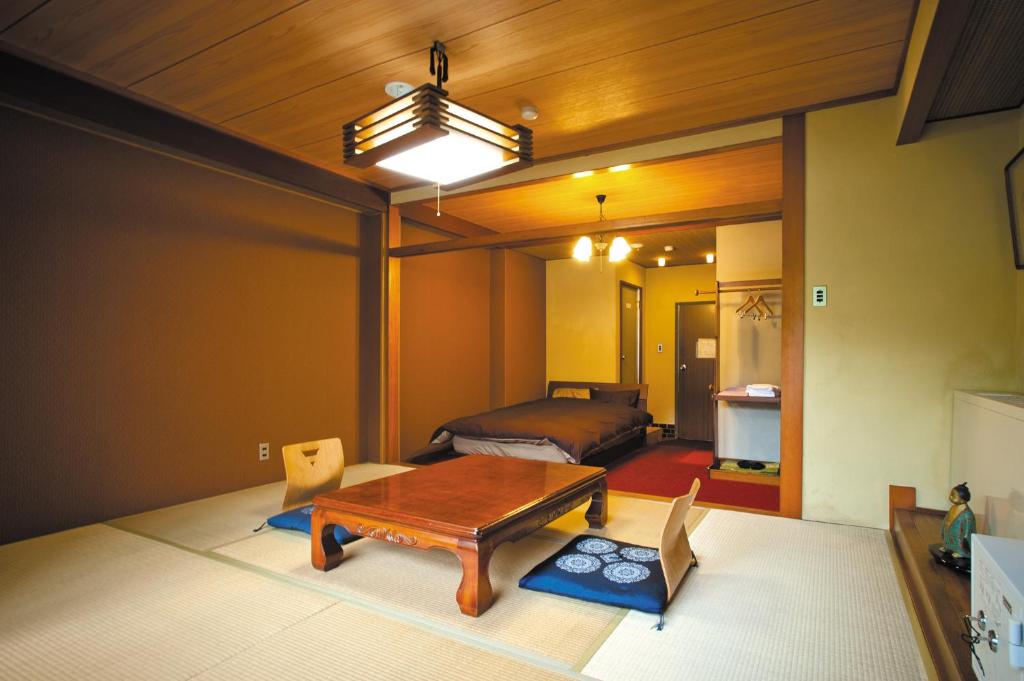 un salon avec une table et un lit dans l'établissement Irori Houraku, à Kamikawa