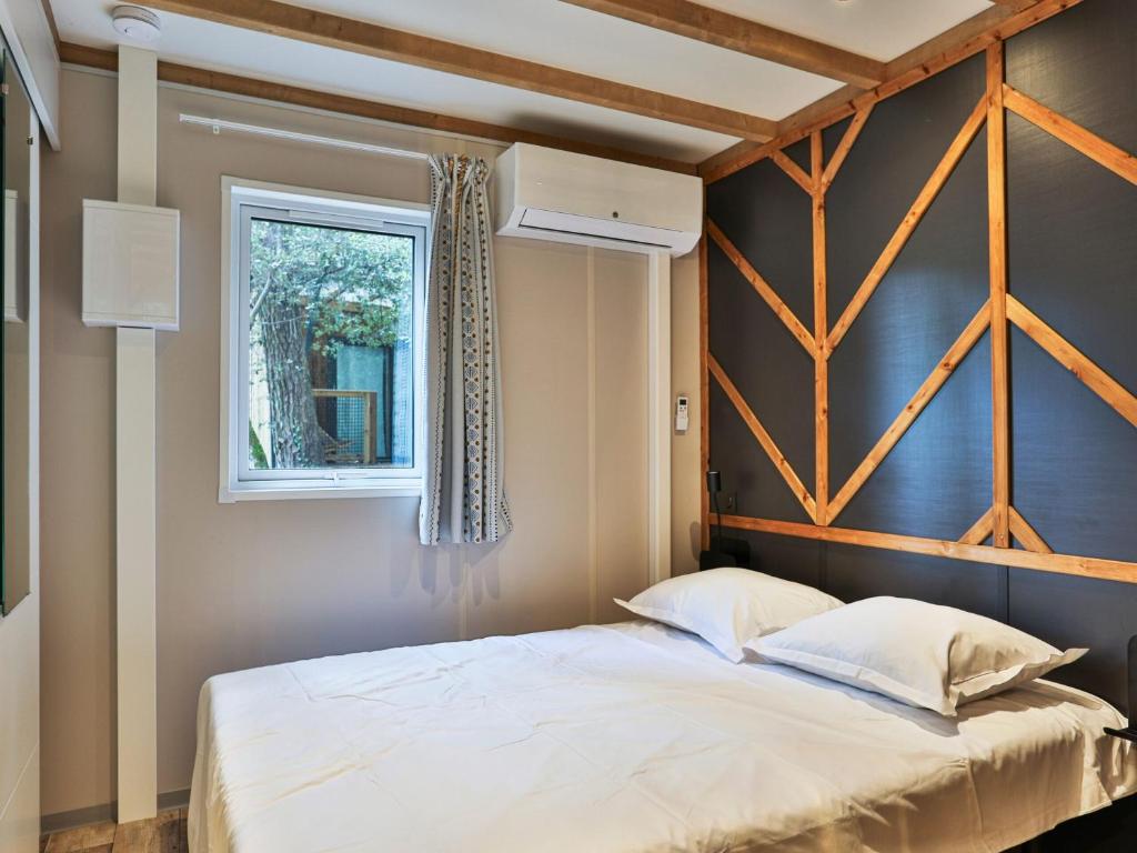 une chambre avec un grand lit avec une fenêtre dans l'établissement Domaine Résidentiel de Plein Air Les Dunes, à Longeville-sur-Mer