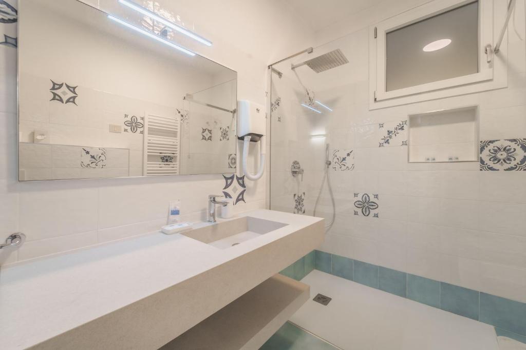 une salle de bain blanche avec lavabo et douche dans l'établissement Hotel Dino, à Capoliveri