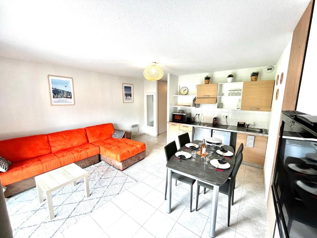 un salon avec un canapé orange et une table dans l'établissement Confort Moderne à Valberg - Terrasse avec Vue Panoramique 100 m des Pistes, à Valberg