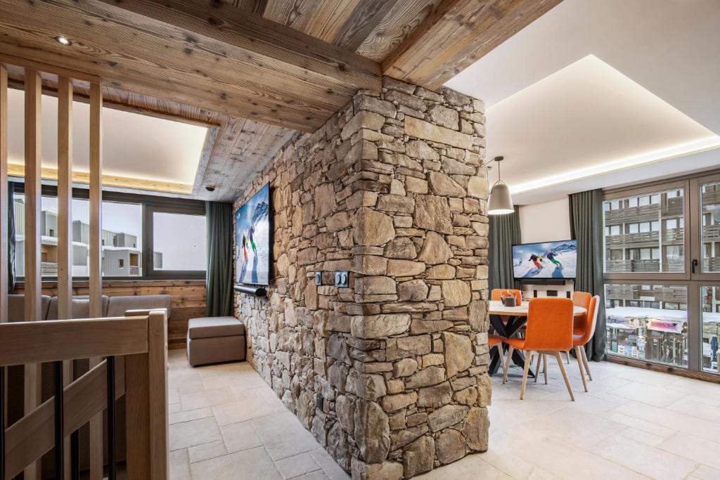 - un mur en pierre dans le salon avec une table et des chaises dans l'établissement Chalet Hôtel Quartz, à Tignes
