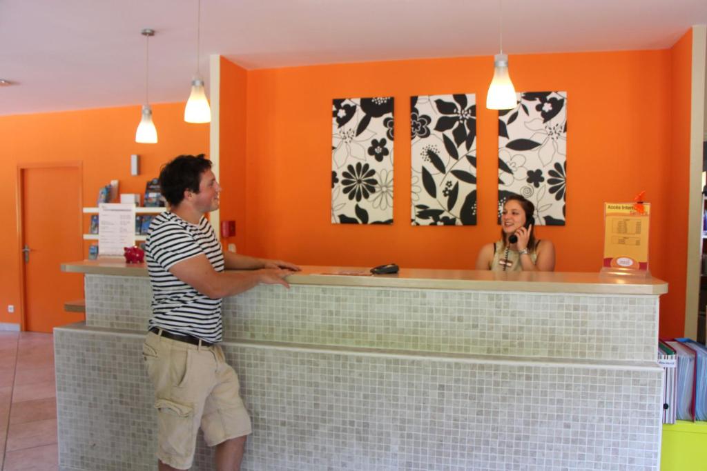 un homme debout devant un comptoir avec une femme dans l'établissement Résidence Lagrange Vacances - Les Cottages Varois, à Solliès-Toucas 37 autres photos