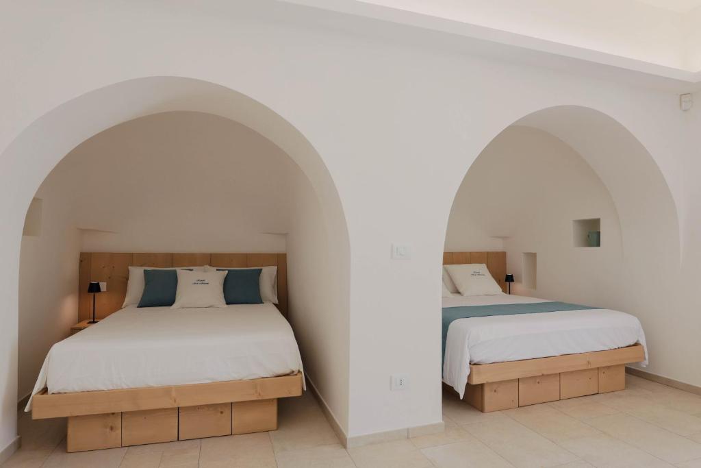 deux lits dans une chambre aux murs blancs dans l'établissement Resort San Giacomo con Piscina, à San Michele Salentino 43 autres photos