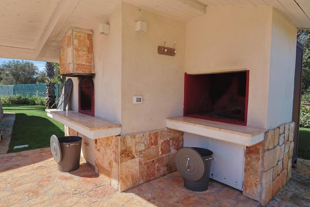 - un four à pizza extérieur avec deux poubelles sur une terrasse dans l'établissement Resort San Giacomo con Piscina, à San Michele Salentino