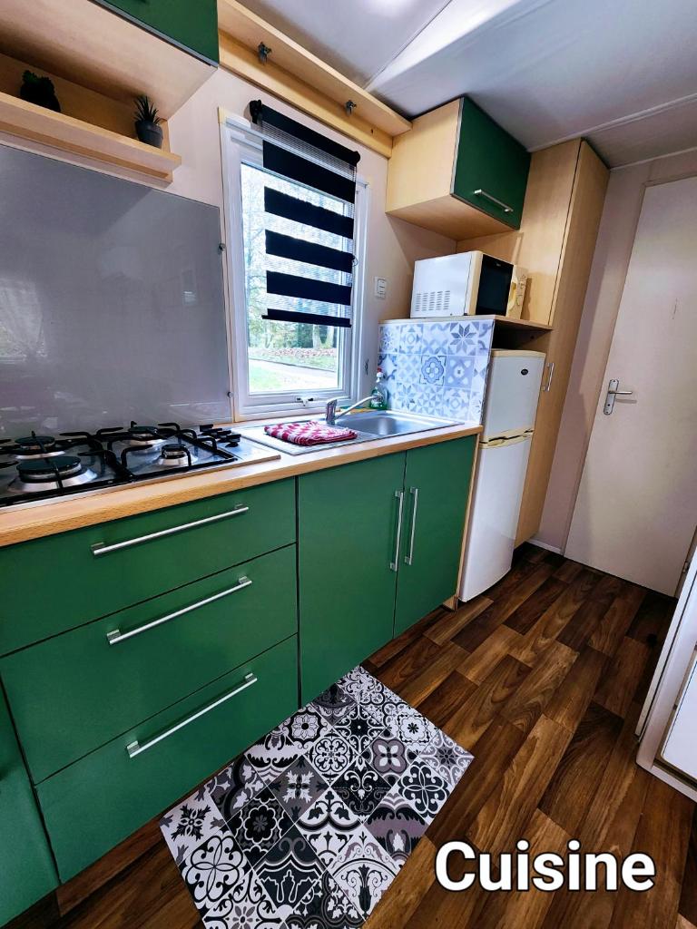 une cuisine avec des armoires vertes et un réfrigérateur blanc dans l'établissement L'indépendant, à Saint-Chéron