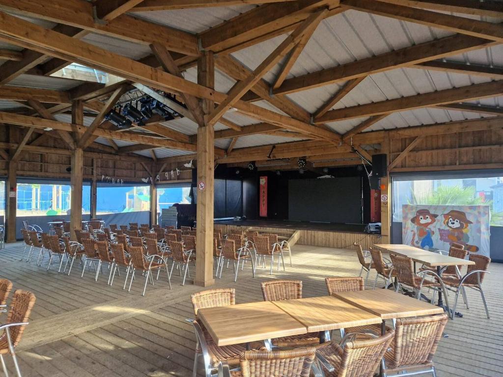 Cette grande chambre dispose de tables, de chaises et d'un écran. dans l'établissement Houlgate Mobilhome,3ch, 6pl, camp 5 étoiles, piscines, club enfants, à Houlgate