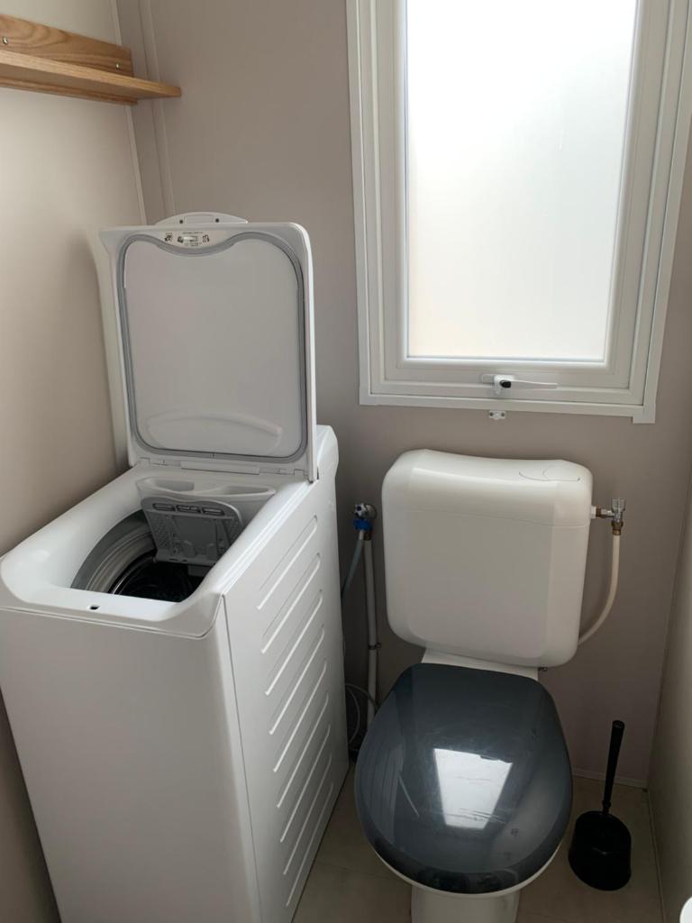 Elle comprend une petite salle de bains pourvue de toilettes et d'une fenêtre. dans l'établissement Siblu Village Les Viviers Bassin d'Arcachon mobile home neuf climatisé 3 chambres, à Lège-Cap-Ferret