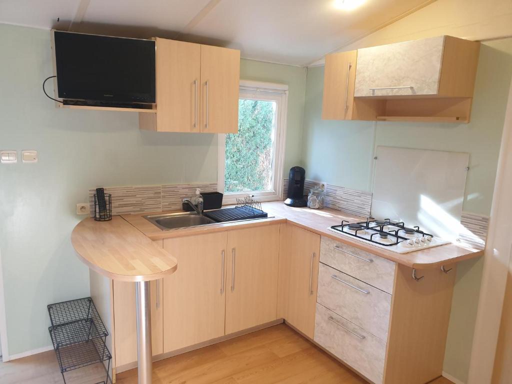 une petite cuisine avec un évier et une cuisinière dans l'établissement Mobil home 4 personnes avec clim, à La Roque-dʼAnthéron