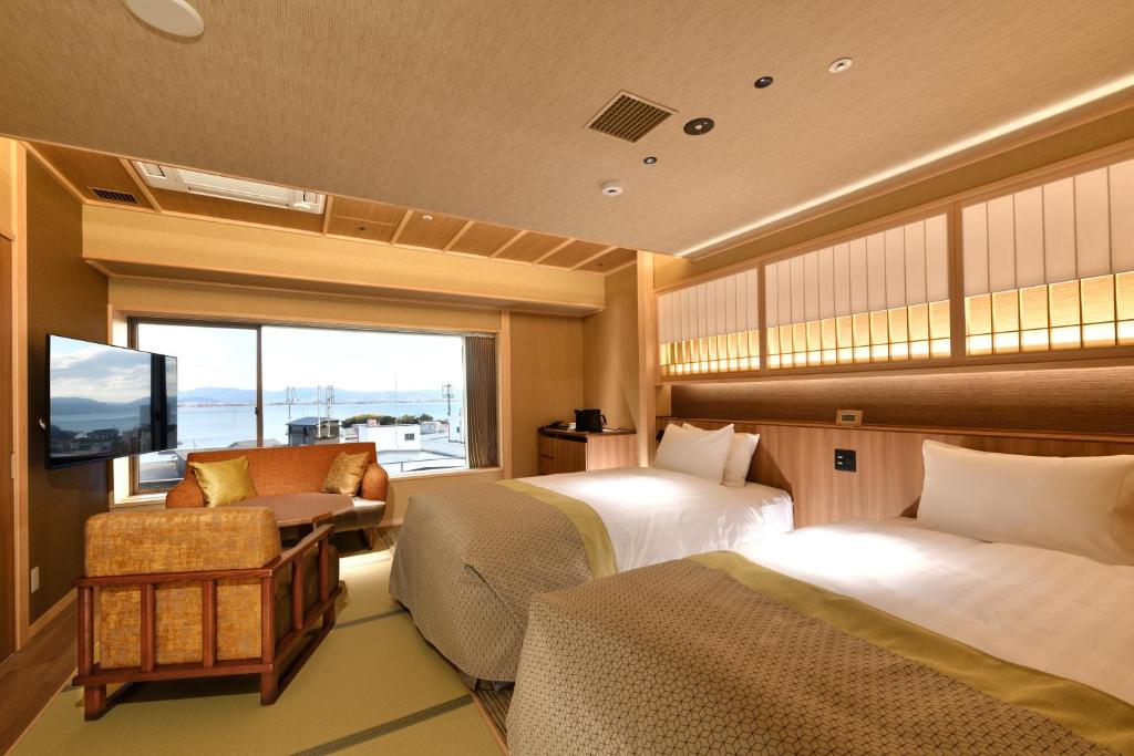 une chambre d'hôtel avec deux lits et une télévision dans l'établissement Yumotokan, à Ōtsu
