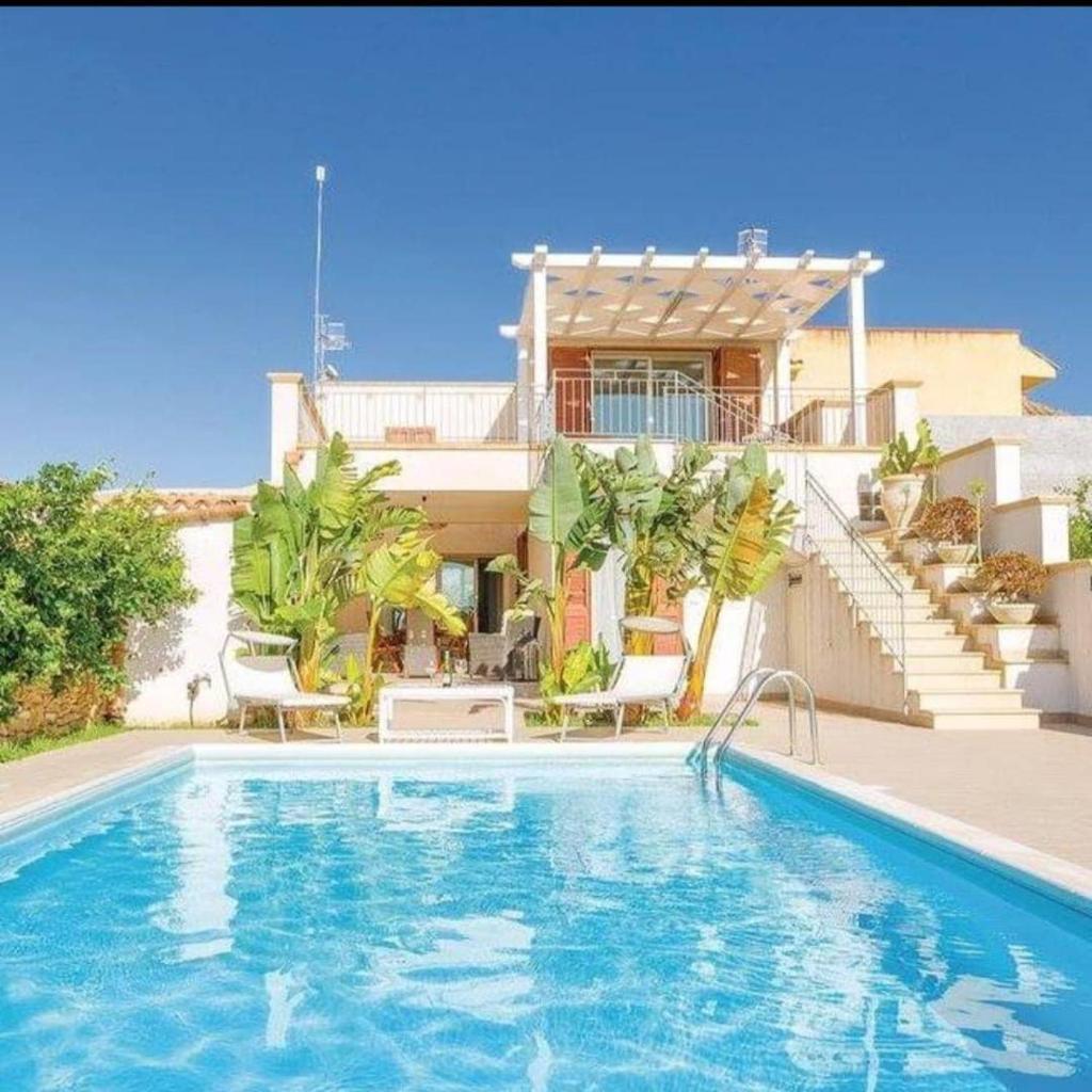 une maison avec une piscine devant une maison dans l'établissement Queen's Bay, à Porto Palo