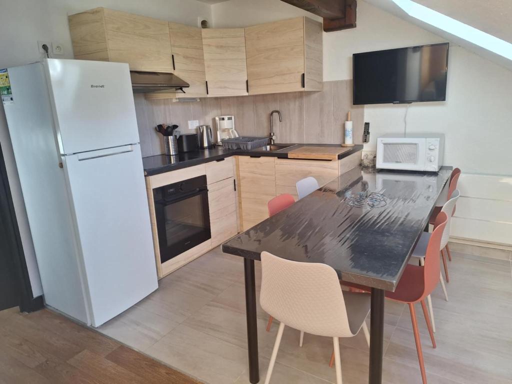 une cuisine avec une table et un réfrigérateur blanc dans l'établissement Saint-Sorlin D'Arves 4-6 personnes pied des pistes 310km de pistes tous niveaux, à Saint-Sorlin-dʼArves