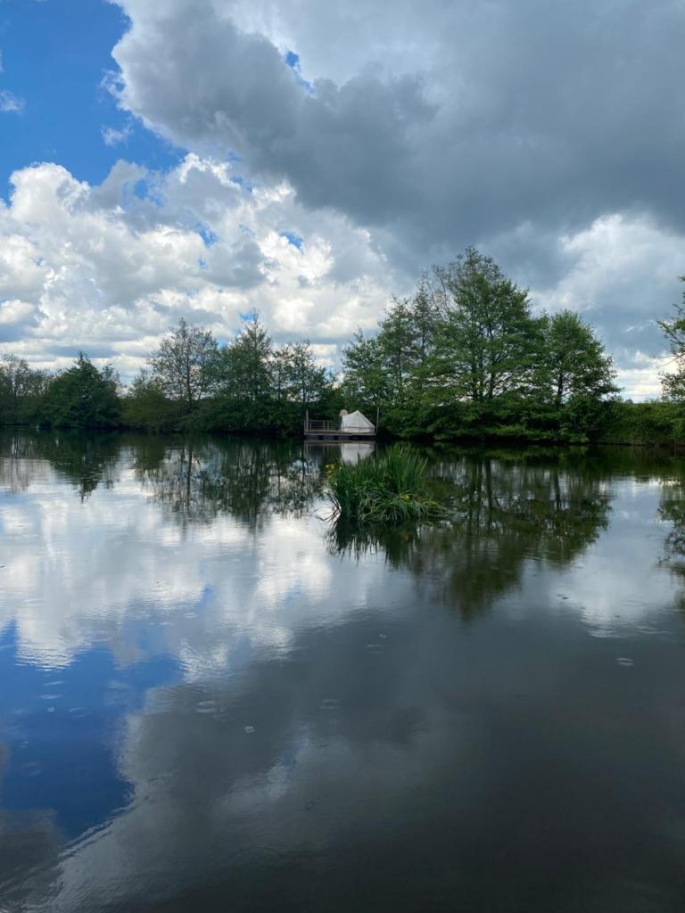 une grande masse d'eau avec des arbres et des nuages dans l'établissement Patouillet bateau naviguant, à Saint-Vincent-sur-Oust