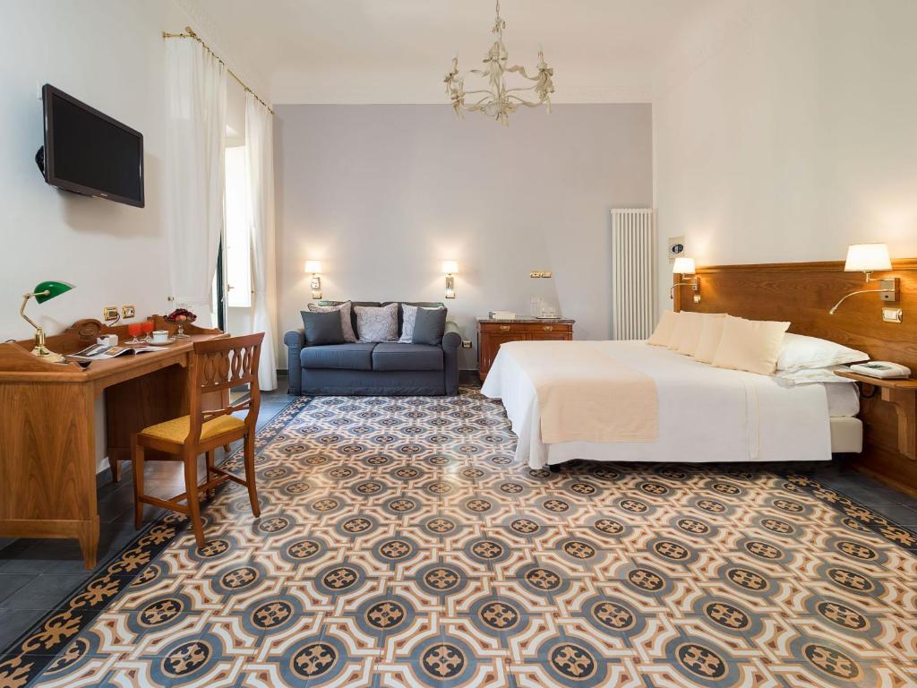 une chambre d'hôtel avec un lit, un bureau et un canapé dans l'établissement Hotel Villa Schuler, à Taormine