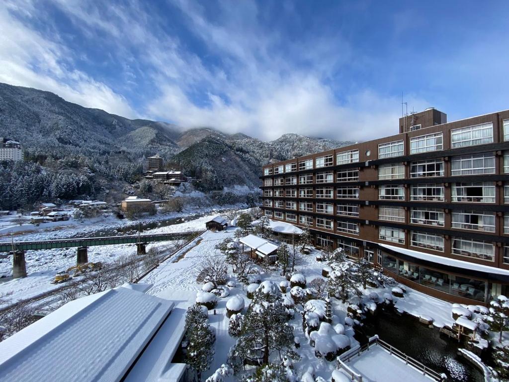 un bâtiment avec de la neige au sol à côté d'un bâtiment dans l'établissement Bosenkan, à Gero