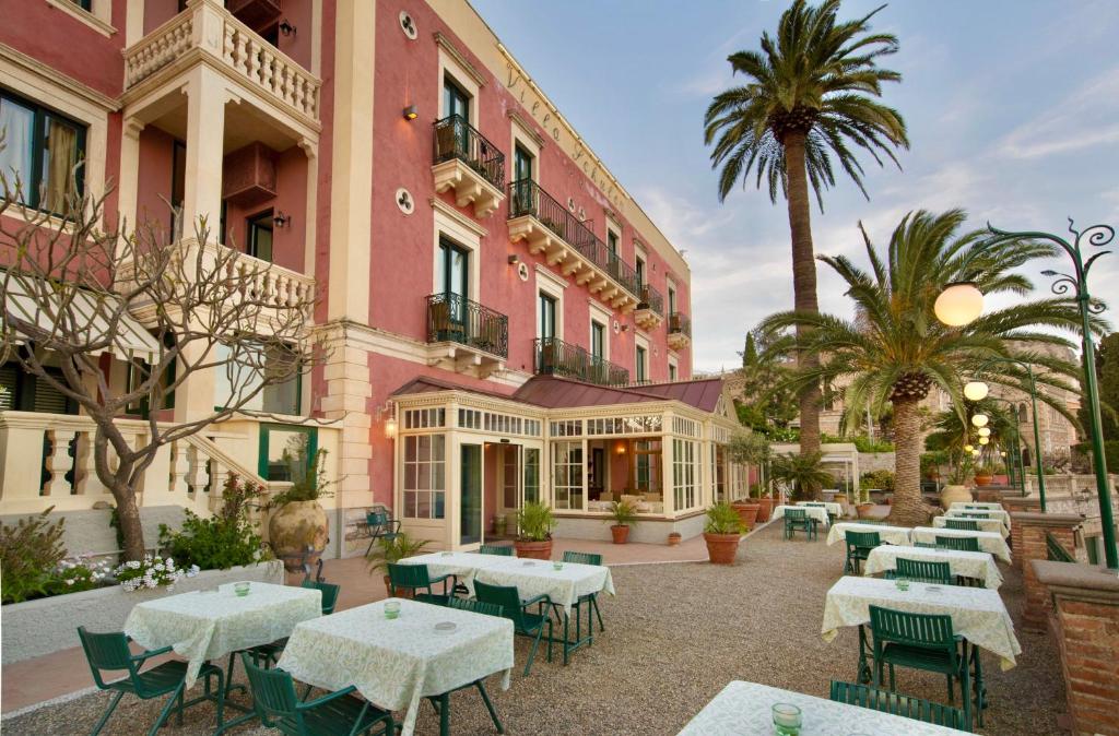 une terrasse avec des tables et des chaises devant un bâtiment dans l'établissement Hotel Villa Schuler, à Taormine