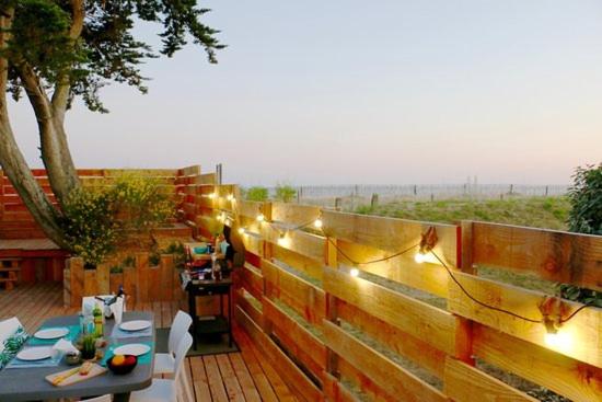 une terrasse en bois avec une table et une clôture éclairée dans l'établissement Camping Landrezac Plage, à Sarzeau