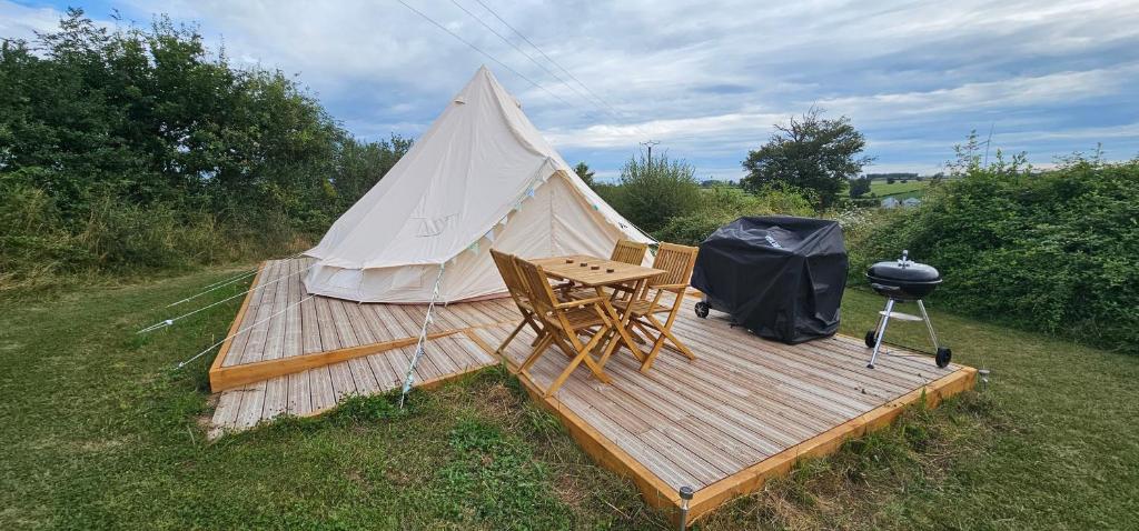 une tente avec une table et un grill sur une terrasse dans l'établissement Camping le Monteil, à Évaux-les-Bains