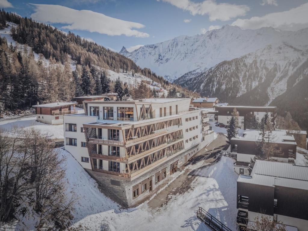 un bâtiment dans la neige avec des montagnes en arrière-plan dans l'établissement TERRESENS - Le Quartz - NEW, à Peisey-Nancroix