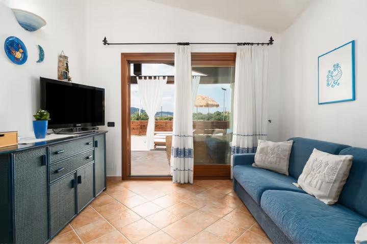 un salon avec un canapé bleu et une télévision dans l'établissement Villa Luna, à Tanaunella