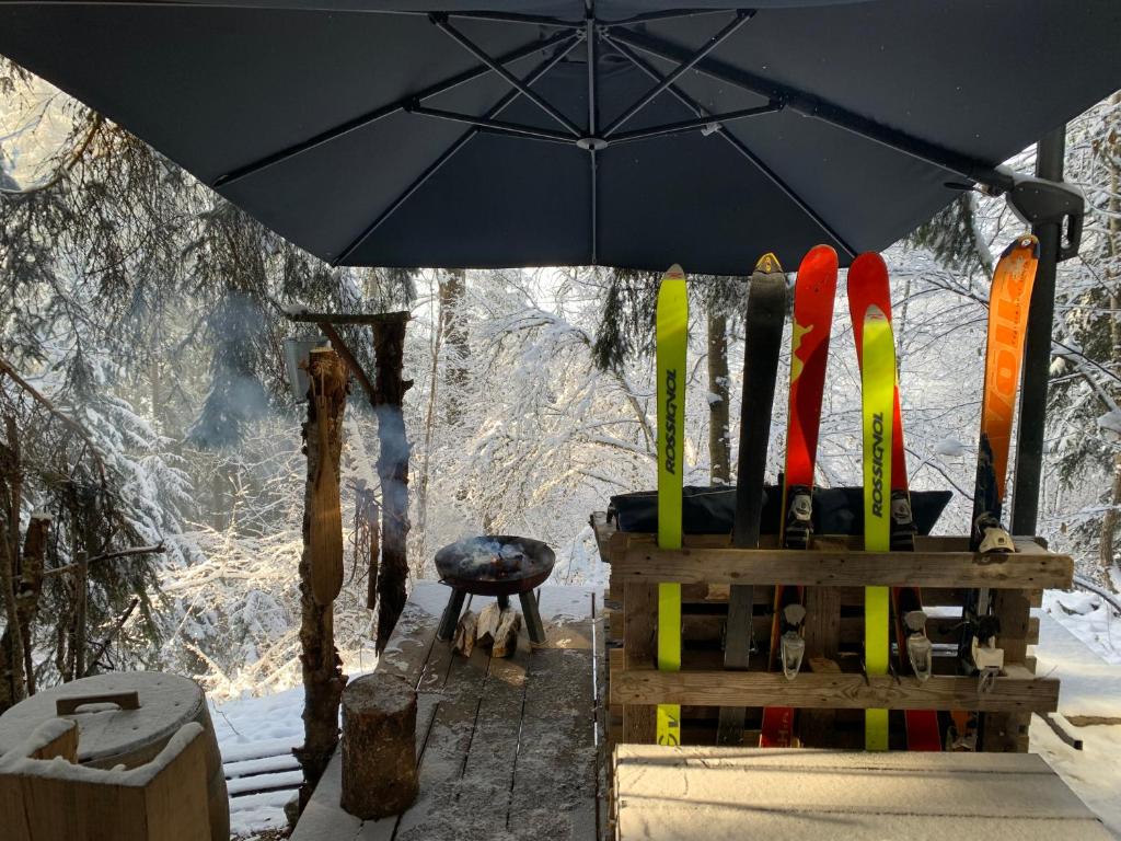 une chaise avec un parasol à côté des skis et de la neige dans l'établissement Mirror globe Kandasphere, à Saint-Gervais-les-Bains