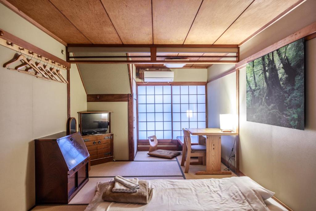 une chambre avec un lit, un bureau et une télévision dans l'établissement Yadoya Hiraiwa, à Kyoto