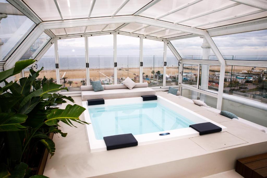 - une piscine au milieu d'un bâtiment avec un plafond en verre dans l'établissement Hotel De Londres, à Rimini