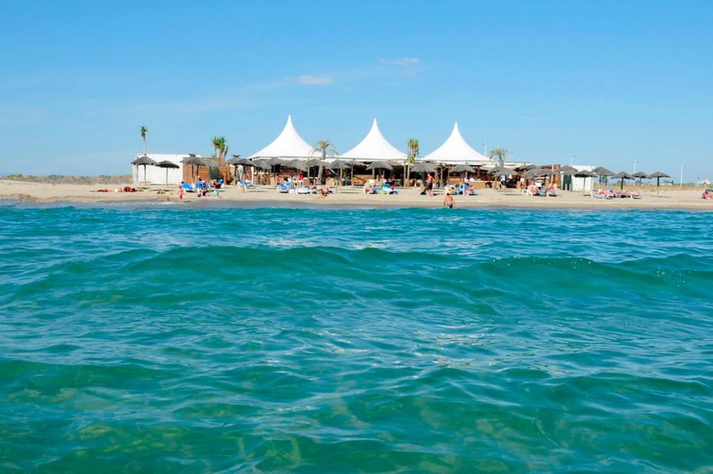- une plage avec un groupe de tentes et l'océan dans l'établissement Mobile-Home 6 pers Camping 4 Etoiles 66140 Idéal Familles, à Canet