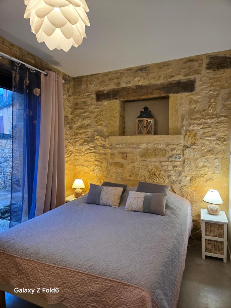une chambre avec un lit et un mur en pierre dans l'établissement Gîte Les Combes Montignac Lascaux, à Montignac