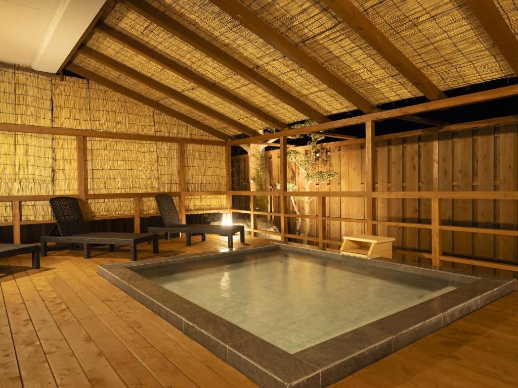 - une piscine dans une pièce avec des chaises et une table dans l'établissement Ooedo Onsen Monogatari Shima Saichoraku, à Shima