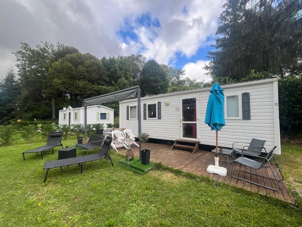 Cette petite caravane blanche dispose d'une terrasse et d'un parasol. dans l'établissement Mobil-Home avec belle exposition, à Saint-Chéron