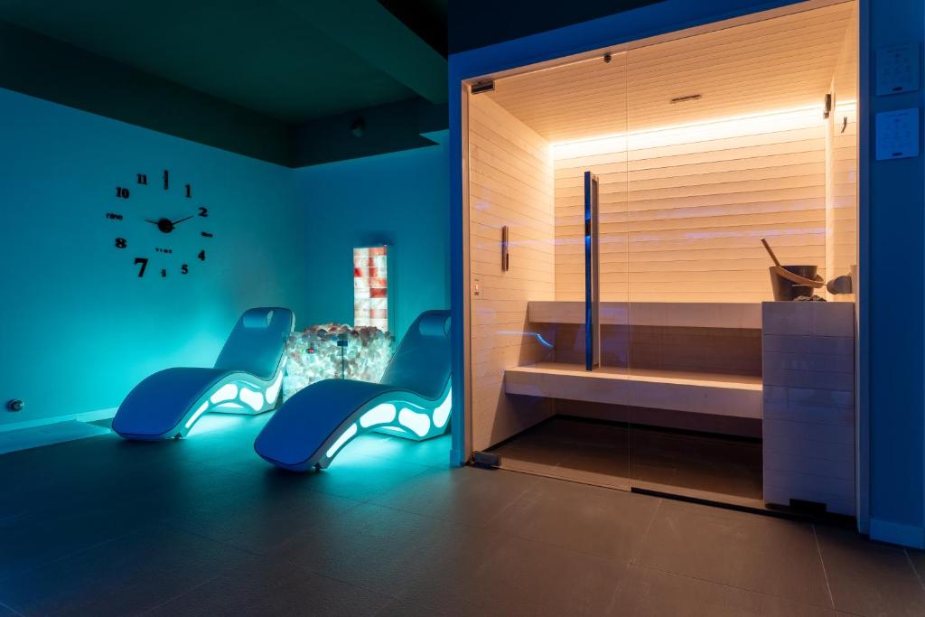 une chambre avec deux chaises bleues et une horloge sur le mur dans l'établissement Hotel Residence Esplanade, à Viareggio