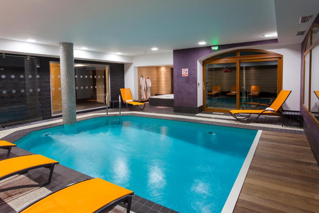 - une piscine dans une chambre d'hôtel avec des chaises jaunes dans l'établissement Le Calgary, aux Saisies