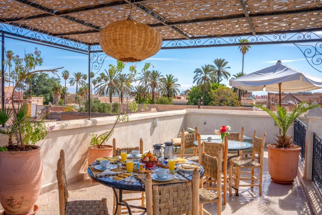 d'une terrasse avec des tables, des chaises et des palmiers. dans l'établissement Riad Nora, à Marrakech