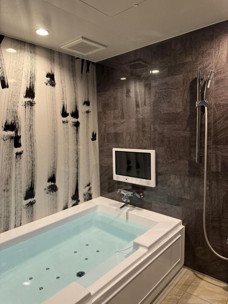 une salle de bain avec une baignoire et une télévision au mur dans l'établissement Dai Tokyo (Adult Only), à Takamatsu